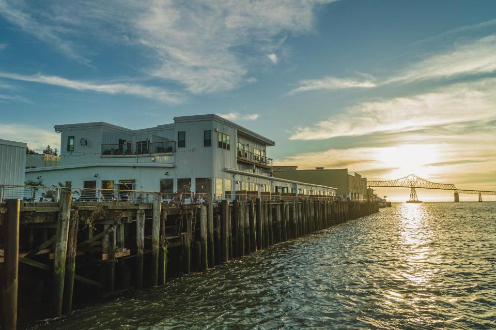 un bâtiment sur une jetée à côté de l'eau avec un pont dans l'établissement Bowline Hotel, à Astoria