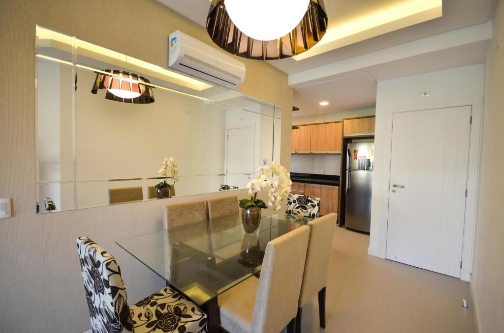 cocina y comedor con mesa de cristal y sillas en 1042 - Apartamento no centro de Bombinhas - Residencial Águas Azuis Apto 203 B, en Bombinhas
