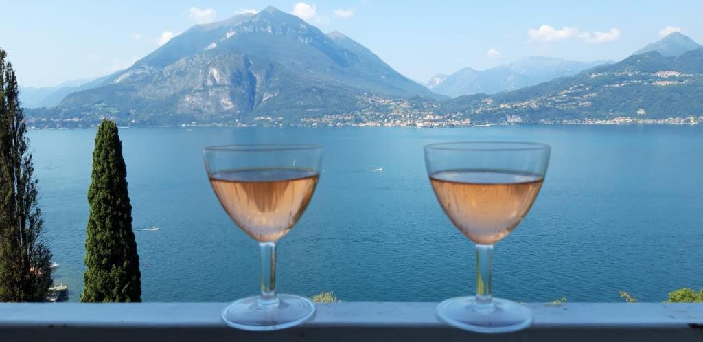 two wine glasses sitting on a ledge overlooking a lake at Varenna Wonders, Villa with pool for 14 guests in Perledo