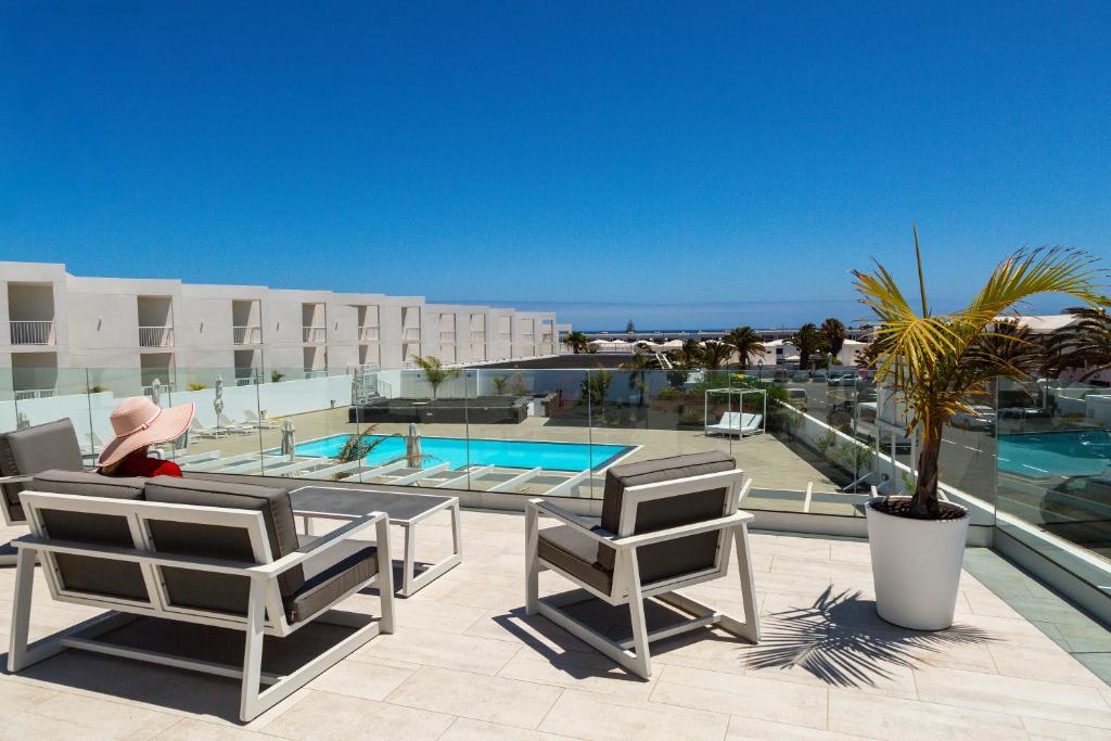 een persoon op een patio met stoelen en een zwembad bij Luxury Senator Apartments in Costa Teguise