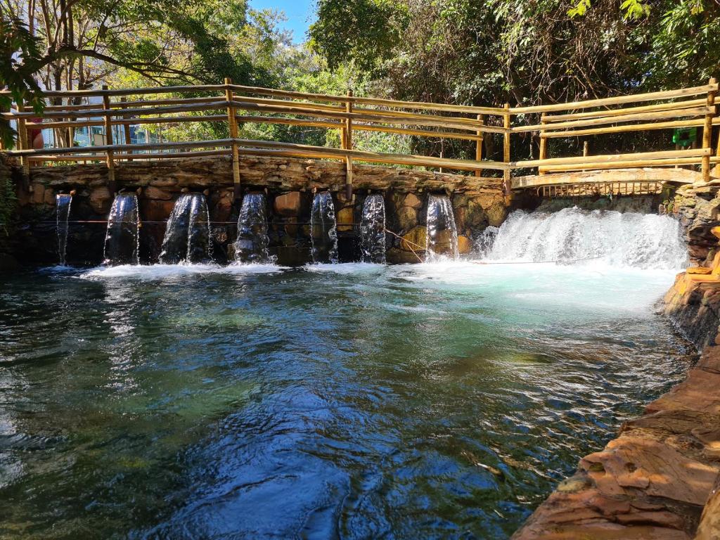 eine Holzbrücke über einen Fluss mit Wasserfällen in der Unterkunft Apto 345 Thermas Paradise in Rio Quente