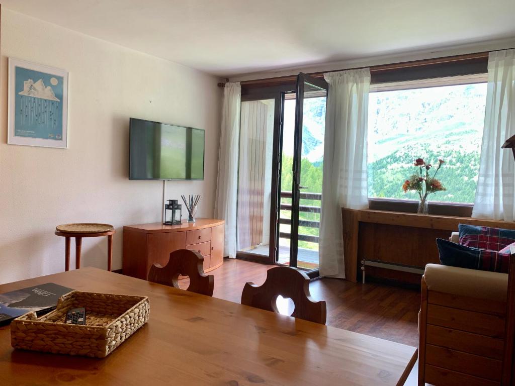 a living room with a table and a large window at Cervinia Ski In Ski Out - Spacious Apartment in Breuil-Cervinia