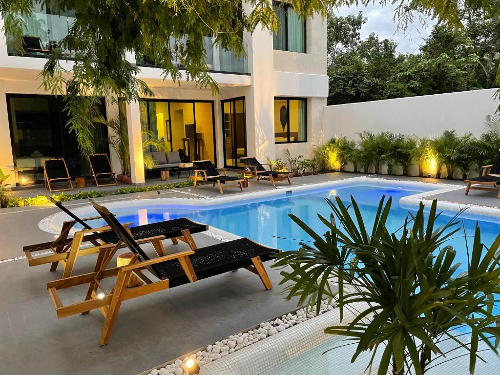 a swimming pool with two lounge chairs next to a house at The Reserve Tulum in Tulum
