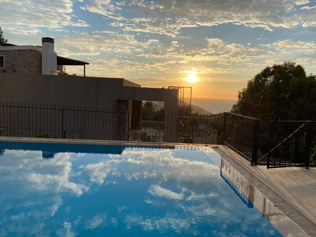 a swimming pool on top of a house with the sunset at Villa Tibet in Yalıkavak