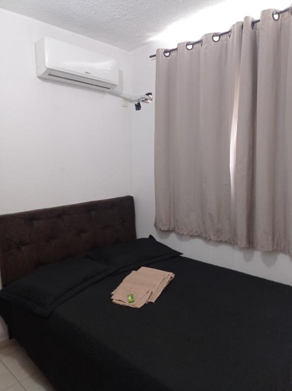 a bedroom with a bed with a black blanket and a window at Lua E Agua X in Campos dos Goytacazes