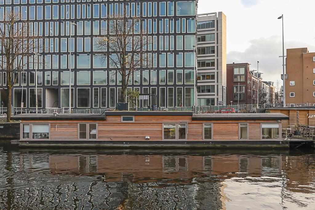 a house boat on the water in front of a building at HouseBoat next to AMSTEL in Amsterdam