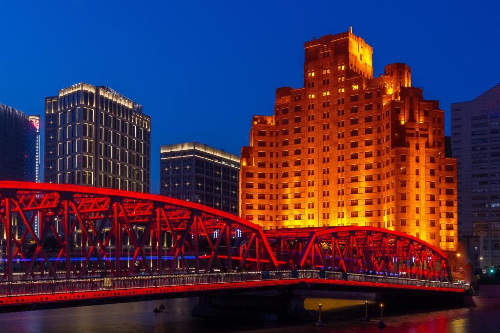 a red bridge over a river in a city at Broadway Mansions Hotel - Bund in Shanghai
