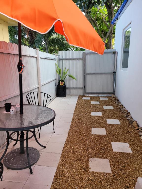 um pátio com uma mesa e um guarda-chuva laranja em Suite Life at Chez Mercedes em Miami