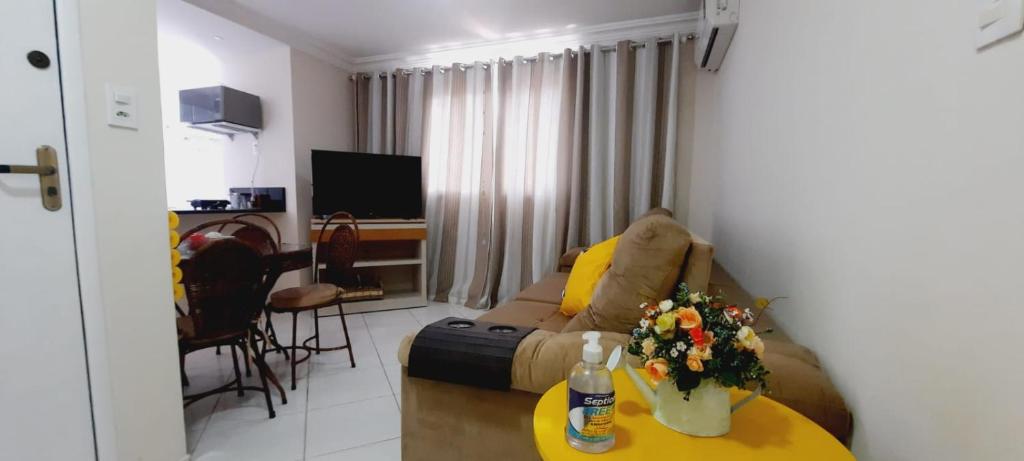 sala de estar con sofá y mesa con flores en Apto Super confortável com Wifi, en Guarapari