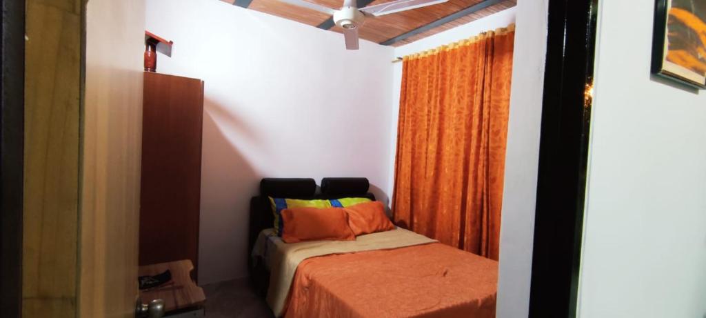 a small bedroom with a bed and an orange curtain at Melgar-Tolima Casa la estrella in Melgar