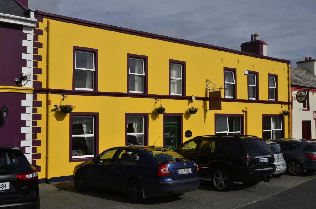 un edificio amarillo con coches estacionados frente a él en Seaview Guesthouse en Allihies