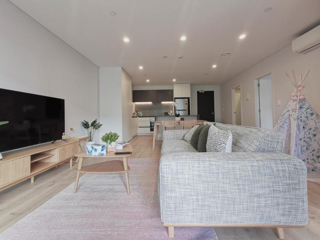 een woonkamer met een bank en een tv bij Brand New Lux 2 Bedroom Apartment in Auckland