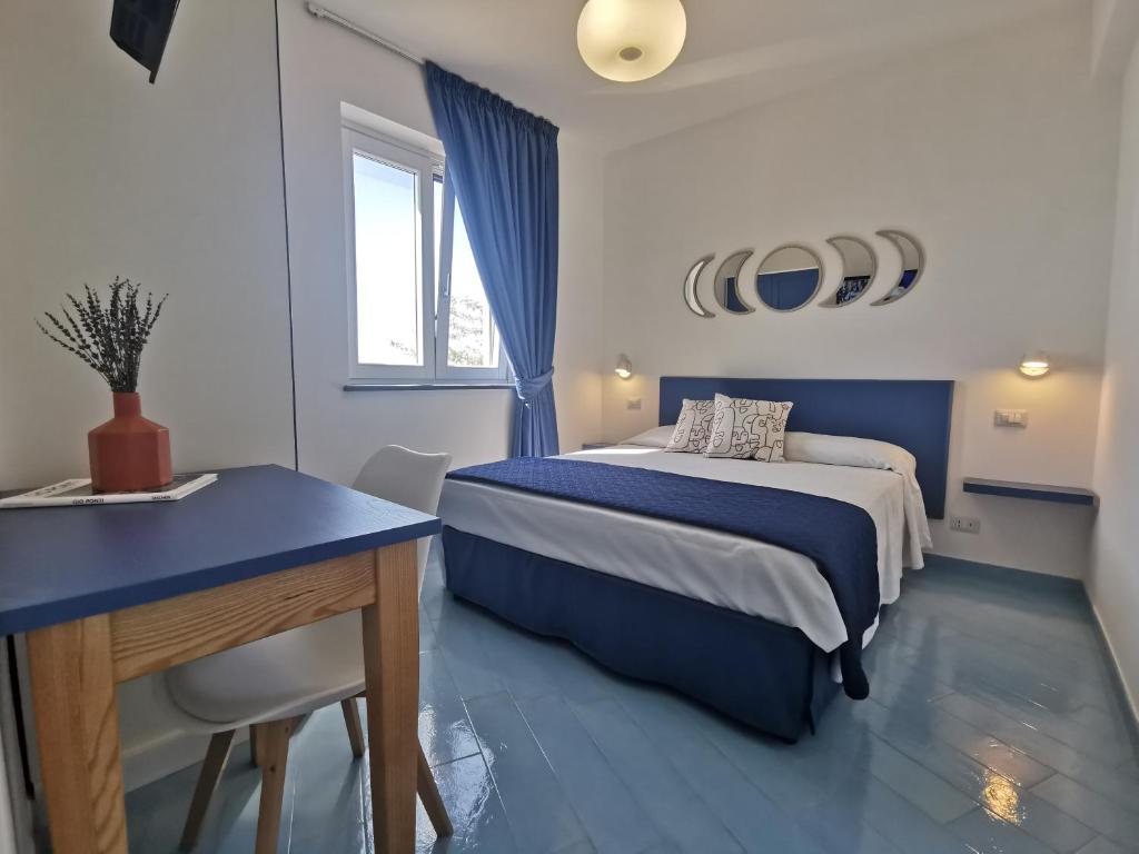 a blue and white bedroom with a bed and a desk at Lena Magda B&B in Furore