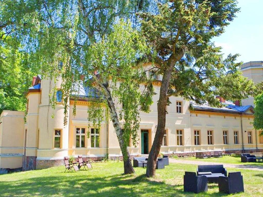 un edificio con un árbol delante de él en Pałac Kursko, en Kursko