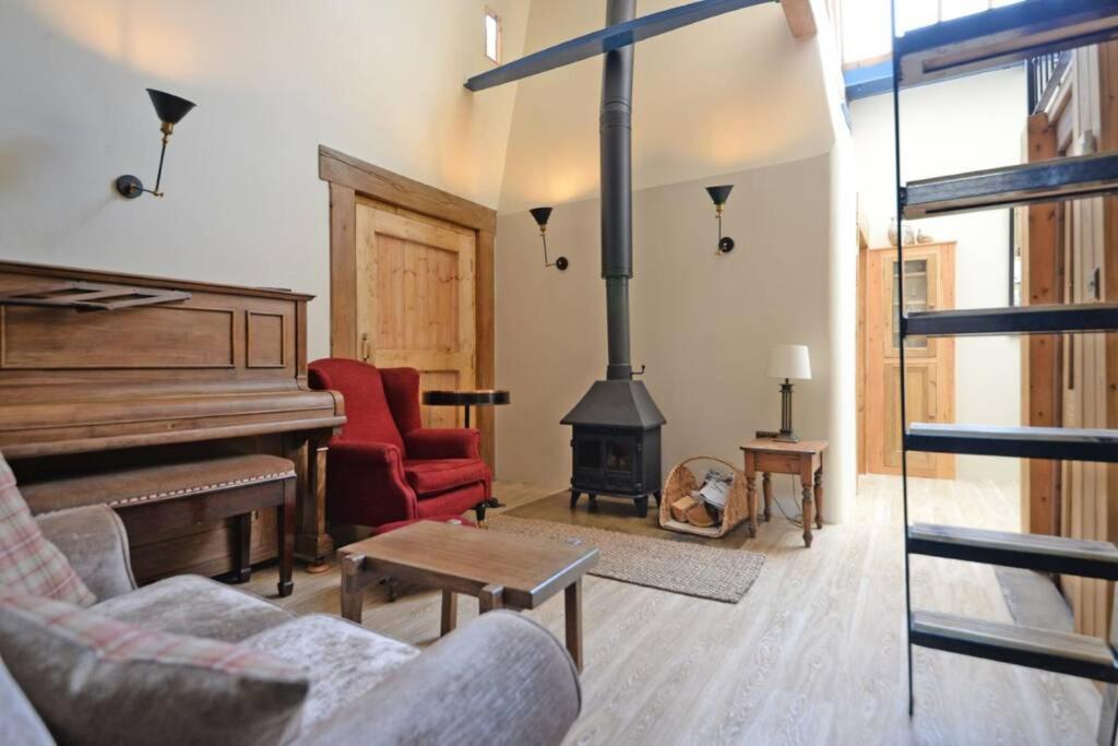 a living room with a fireplace and a piano at Shed End, in 18th century Lothersdale Mill BD20 8EN in Lothersdale