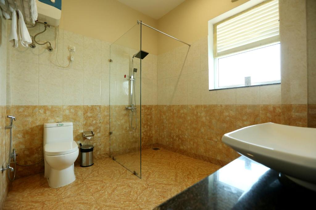a bathroom with a shower and a toilet and a sink at Resort De Coracao - Corbett , Uttarakhand in Rāmnagar