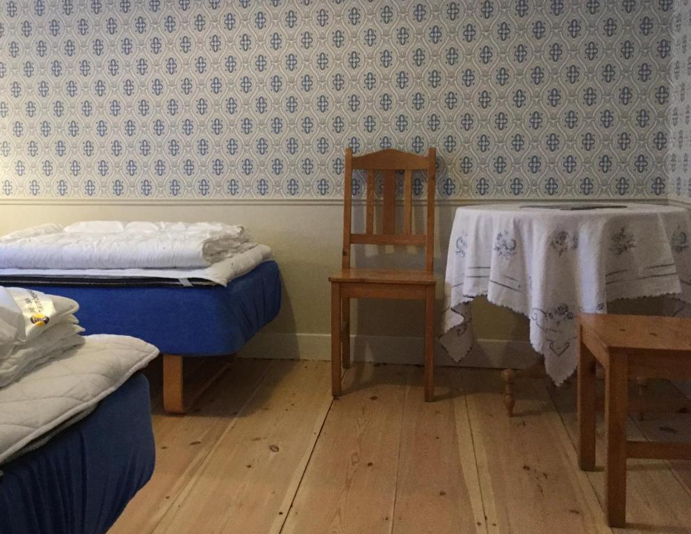 a room with two beds and a chair and a table at STF Vandrarhem Edsbyn in Edsbyn
