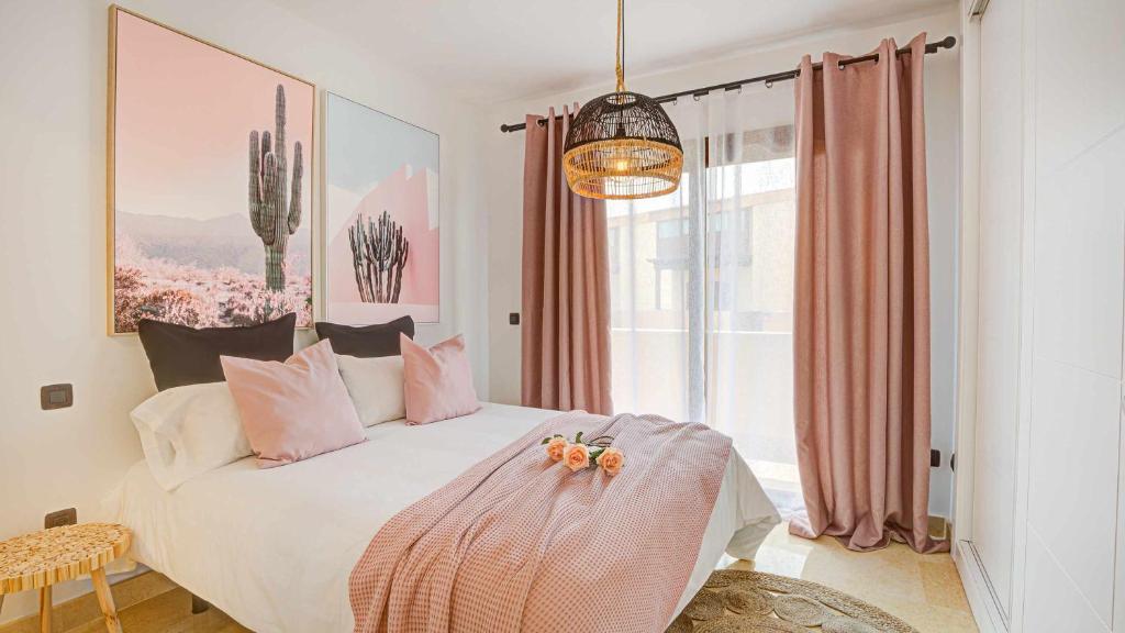 a bedroom with a bed with pink pillows and a window at Tinajas Chic in Corralejo