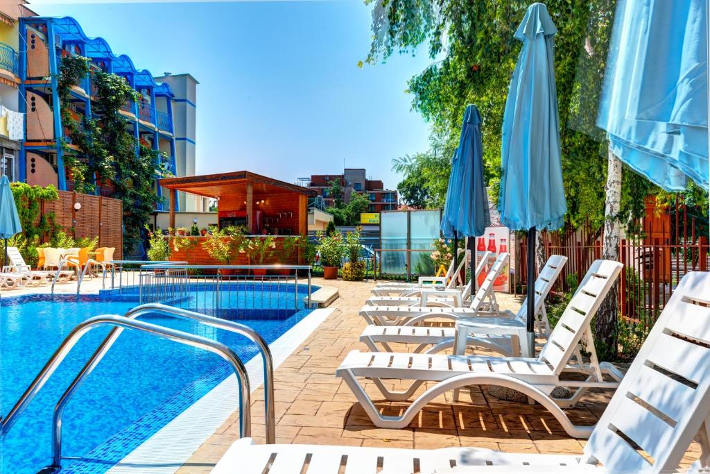 a pool with chaise lounge chairs and umbrellas at Paloma - in the center of the city in Sunny Beach