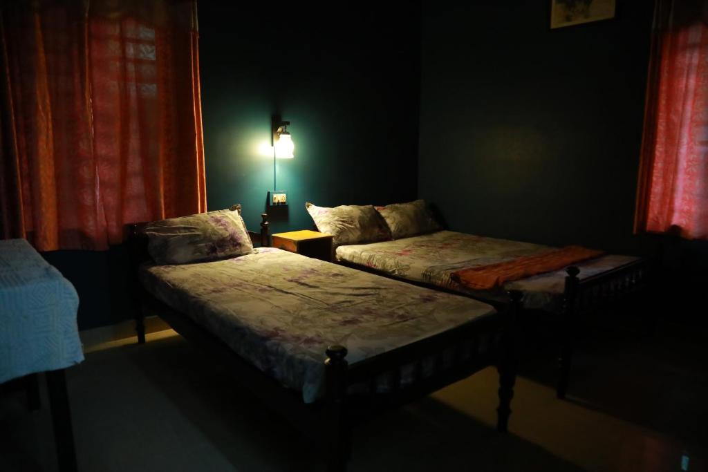 a dark room with two beds and a lamp at Sajeev Home Stay in Cherai Beach
