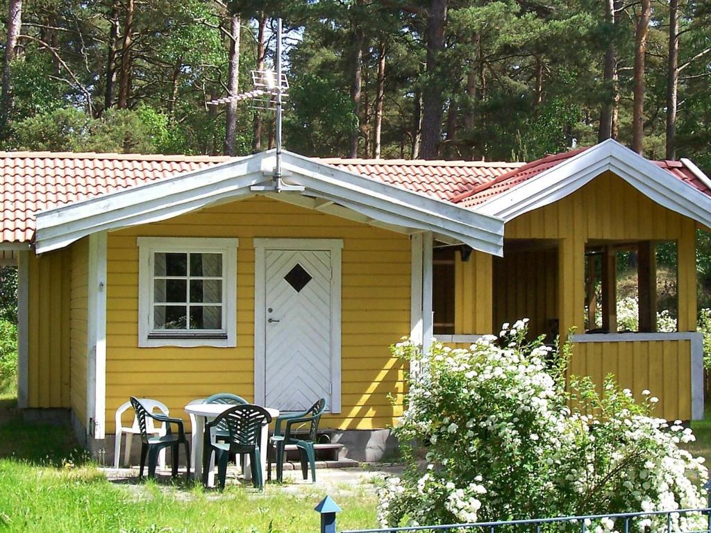 a yellow house with chairs and a table in front of it at 5 person holiday home in MELLBYSTRAND in Mellbystrand