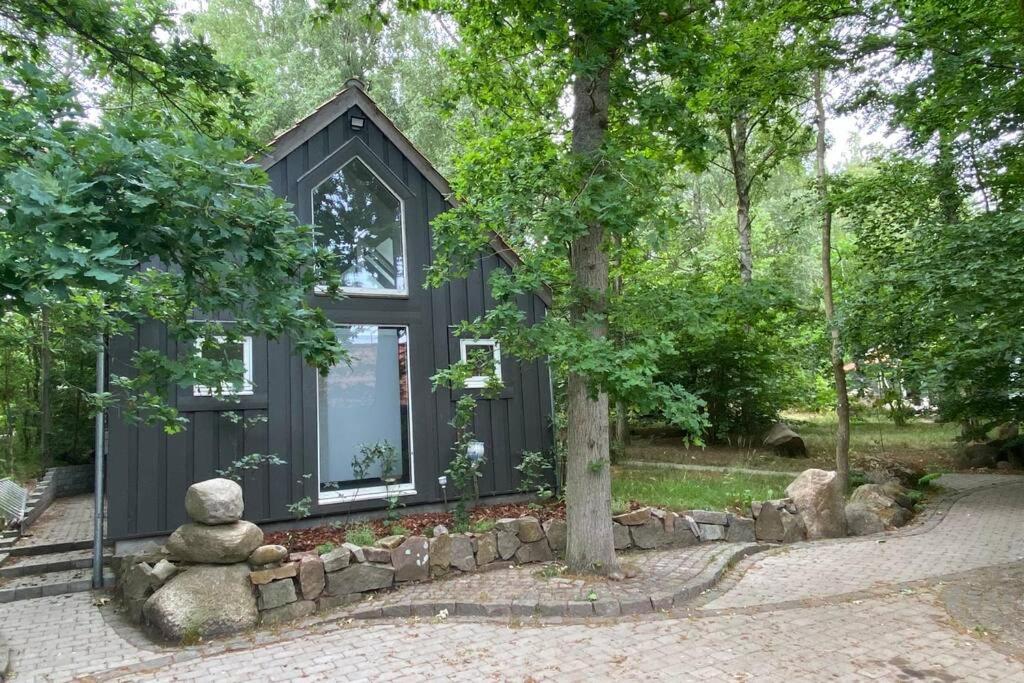 a black tiny house with a stone wall at Oak Cottage near Rønne & Beach in Rønne