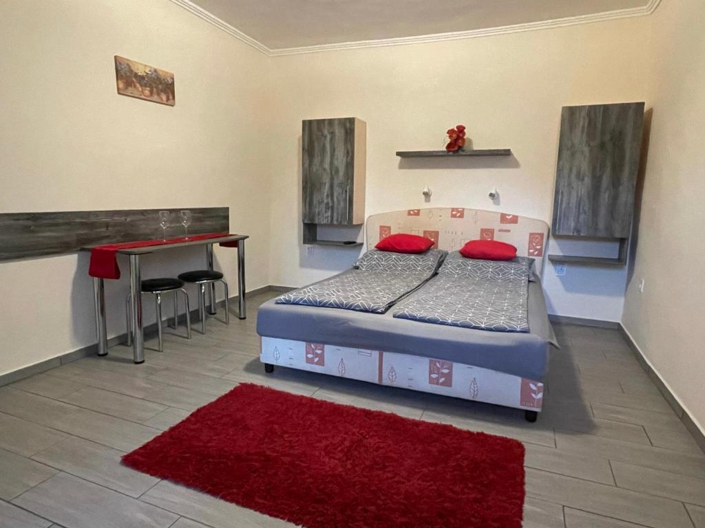 - une chambre avec un lit, un bureau et un tapis rouge dans l'établissement Lina Apartmanok, à Hajdúszoboszló
