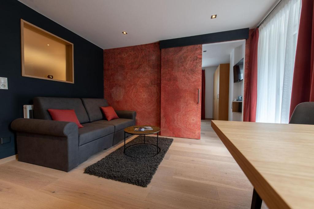 - un salon avec un canapé et une table dans l'établissement Lapis Monti - Apartments & Suites, à Burgusio