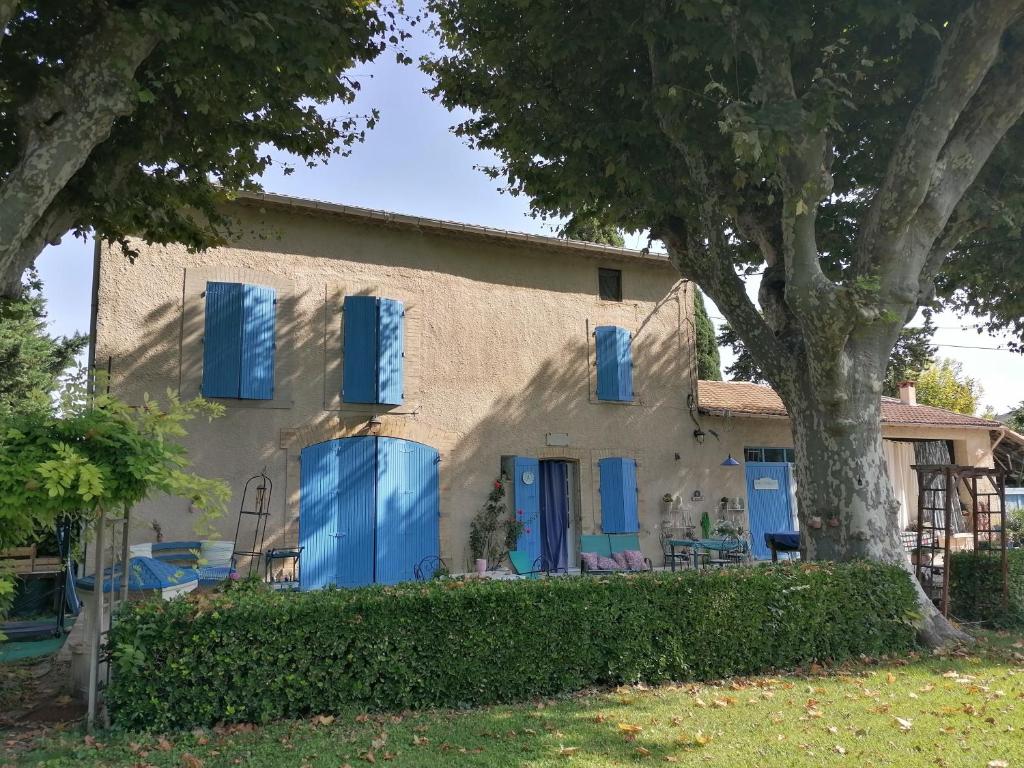 une maison avec des volets bleus et un arbre dans l'établissement Notre campagne provençale, à Avignon