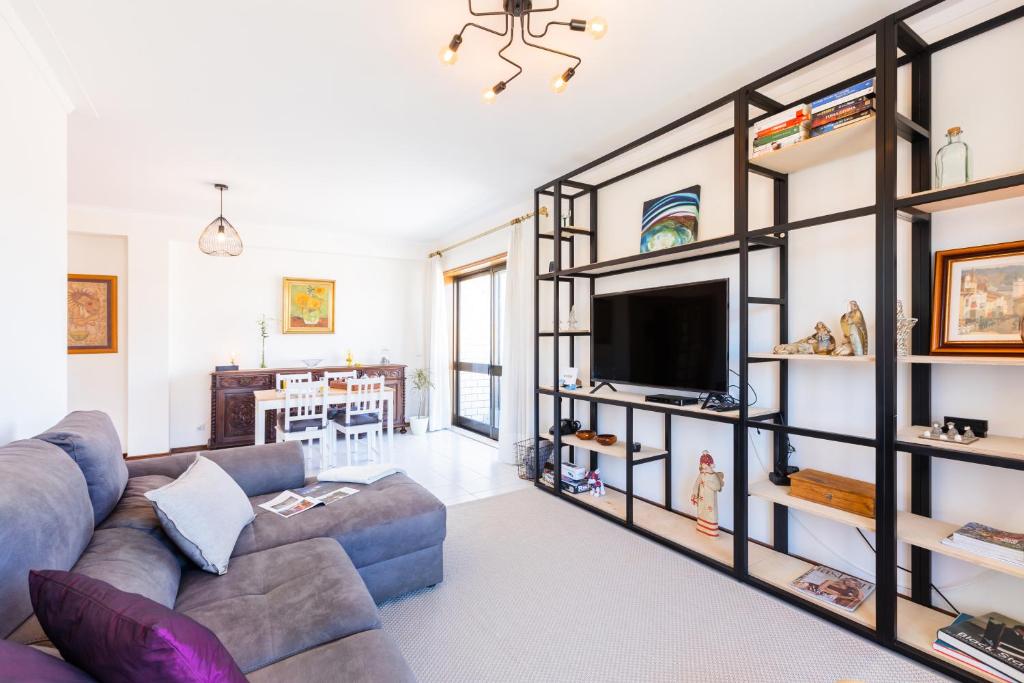 a living room with a couch and a tv at Espinho Sunshine Flat in Espinho