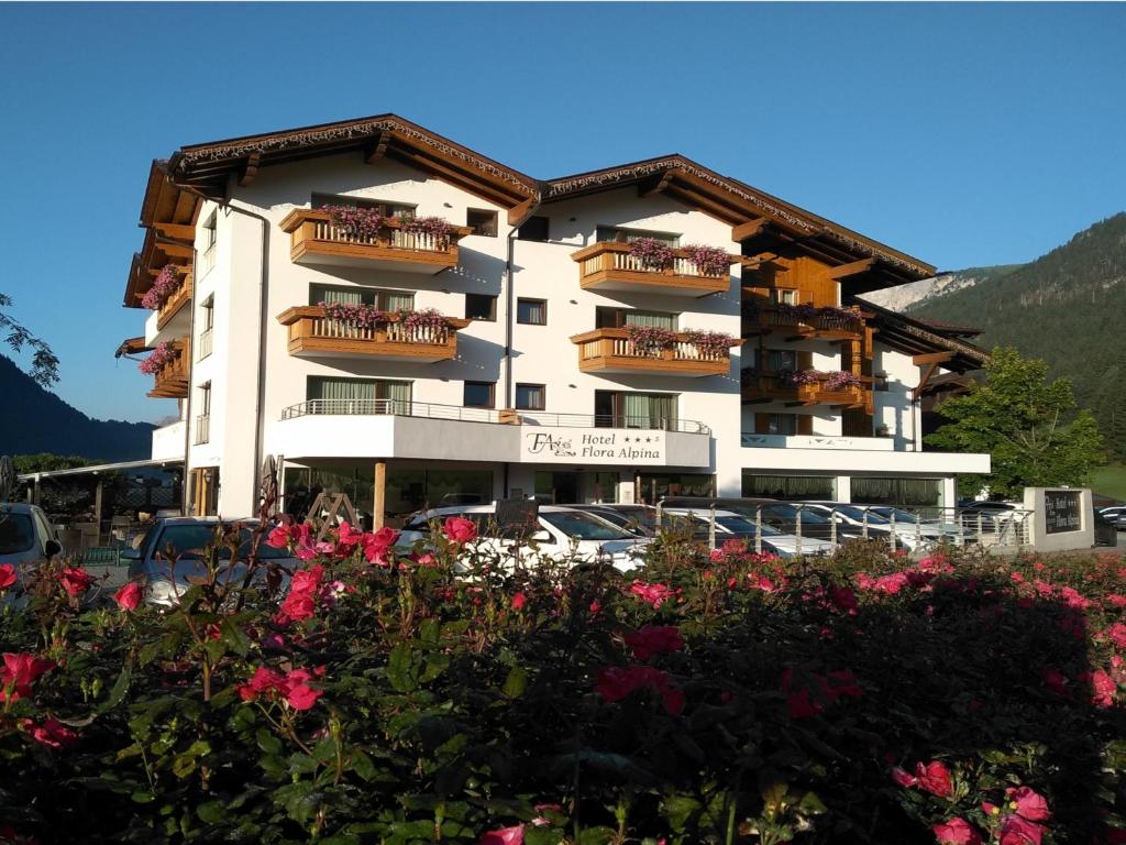 a large building with flowers in front of it at Hotel Flora Alpina in Campitello di Fassa