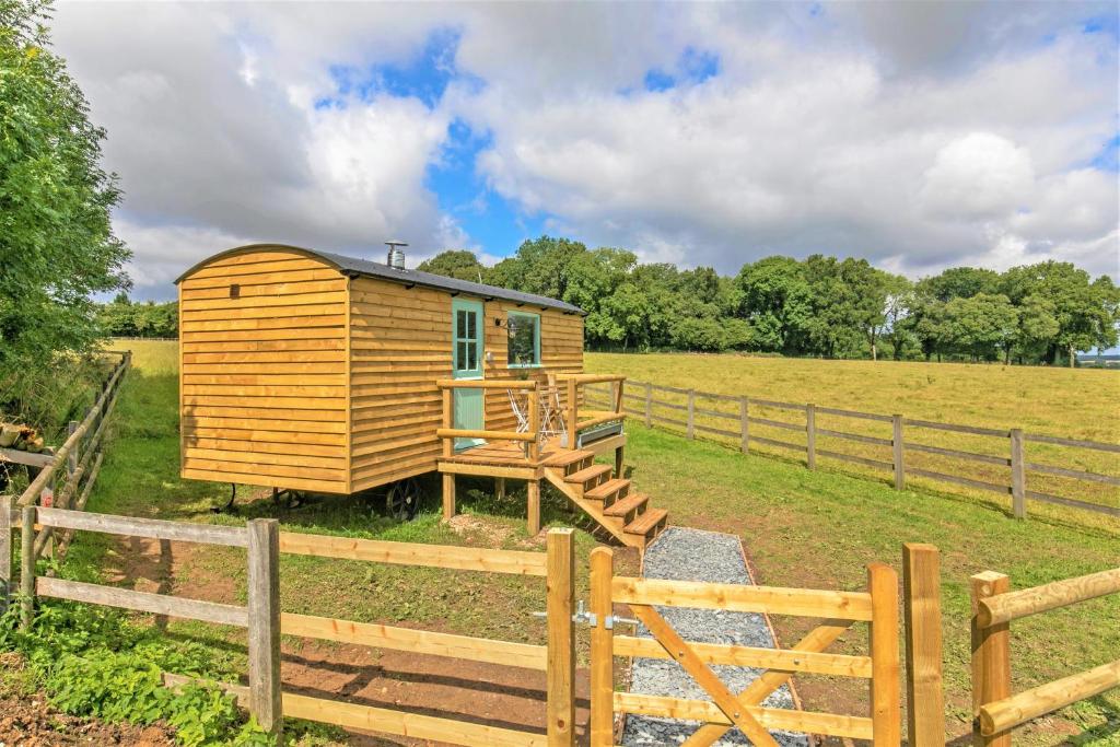 a wooden cabin in a field next to a fence at Jabba, The Hut in Winchester