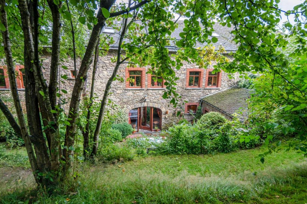 uma casa de pedra com janelas vermelhas e árvores em Dri les Courtils em La-Roche-en-Ardenne
