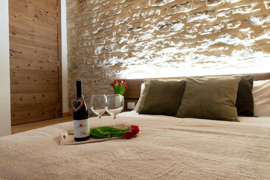a bottle of wine and two glasses on a bed at Antico Borgo Brunelli in Conco