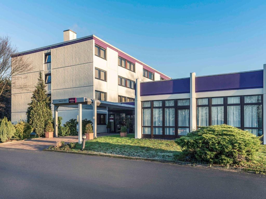 a large building with a gas station in front of it at Mercure Düsseldorf Airport in Ratingen