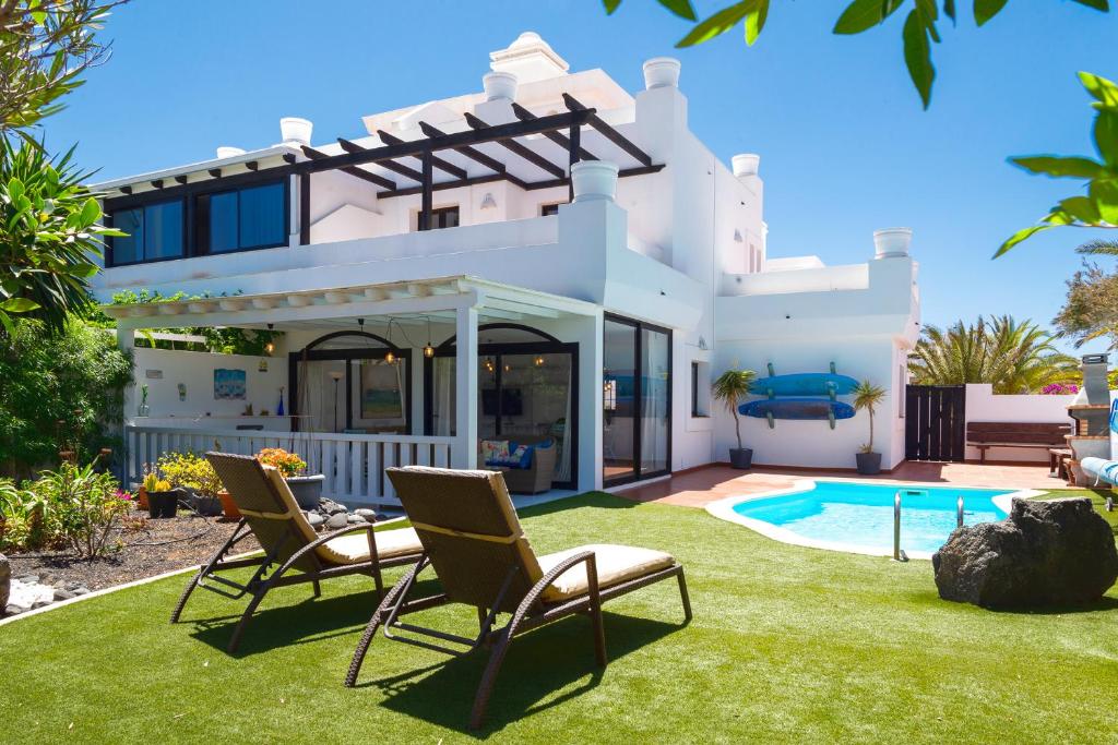 a house with a yard with chairs and a swimming pool at Villa Simba in Corralejo