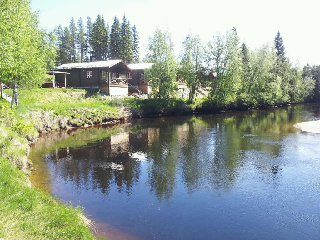 a log cabin next to a river with a house at Vålkojan Naturby - Timber cottages in Vemdalen