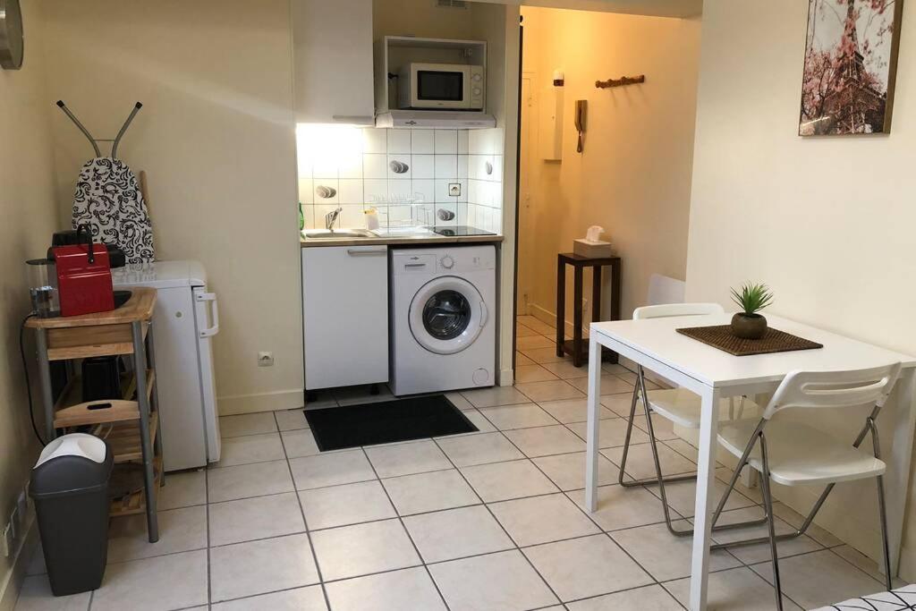 eine Küche mit einer Waschmaschine und einem Tisch mit Stühlen in der Unterkunft Studio Cosy 2 PERS in Longjumeau