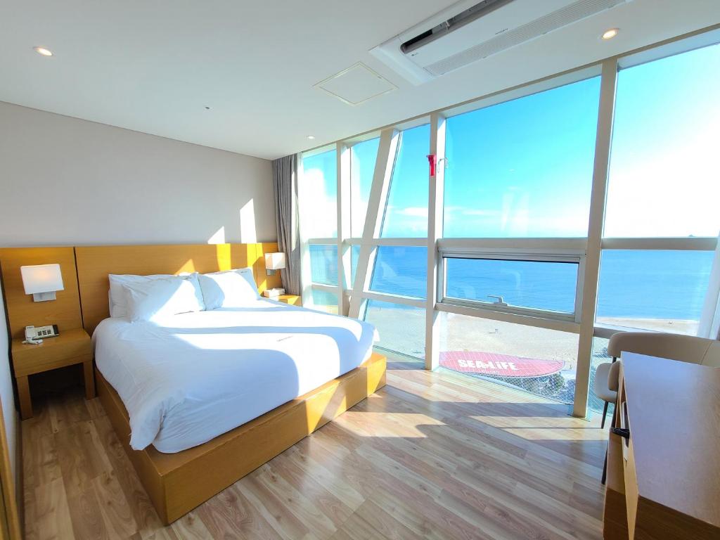 a bedroom with a bed with a view of the ocean at MS Hotel Haeundae in Busan