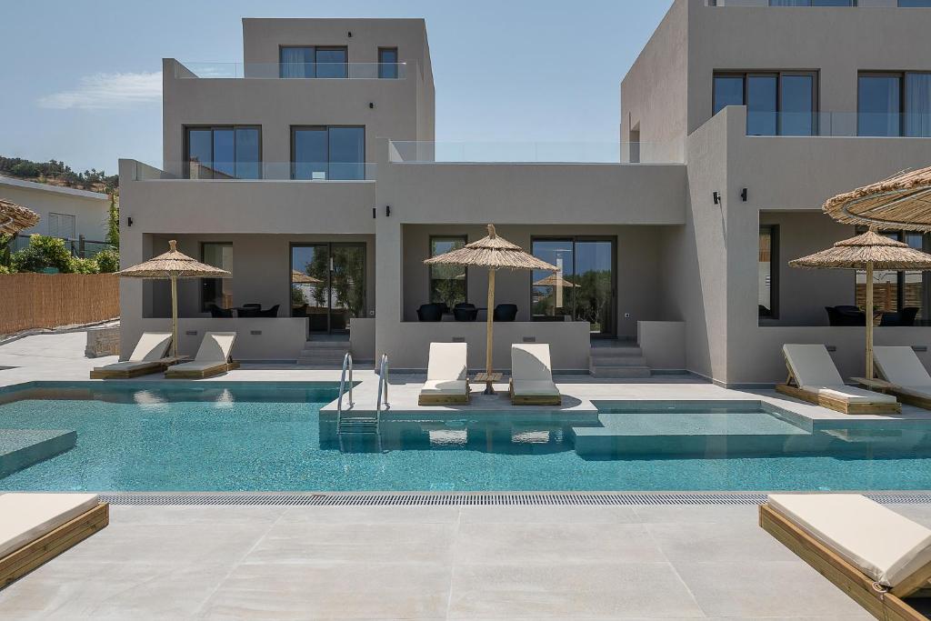 una villa con piscina con sedie e ombrelloni di Casa Nostos ad Agia Marina Nea Kydonias