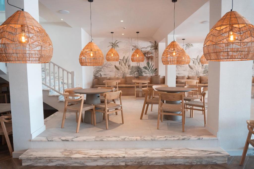 een restaurant met tafels en stoelen en hanglampen bij Portomar Apartments in Portocolom