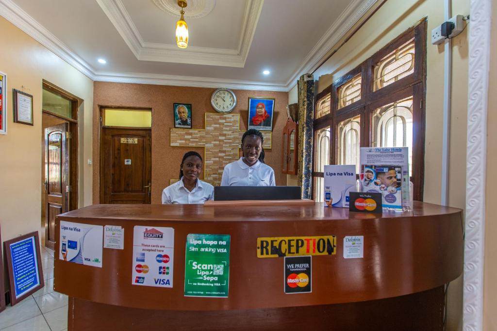 two men standing behind a counter in a room at The Lahe Hotels in Mwanza