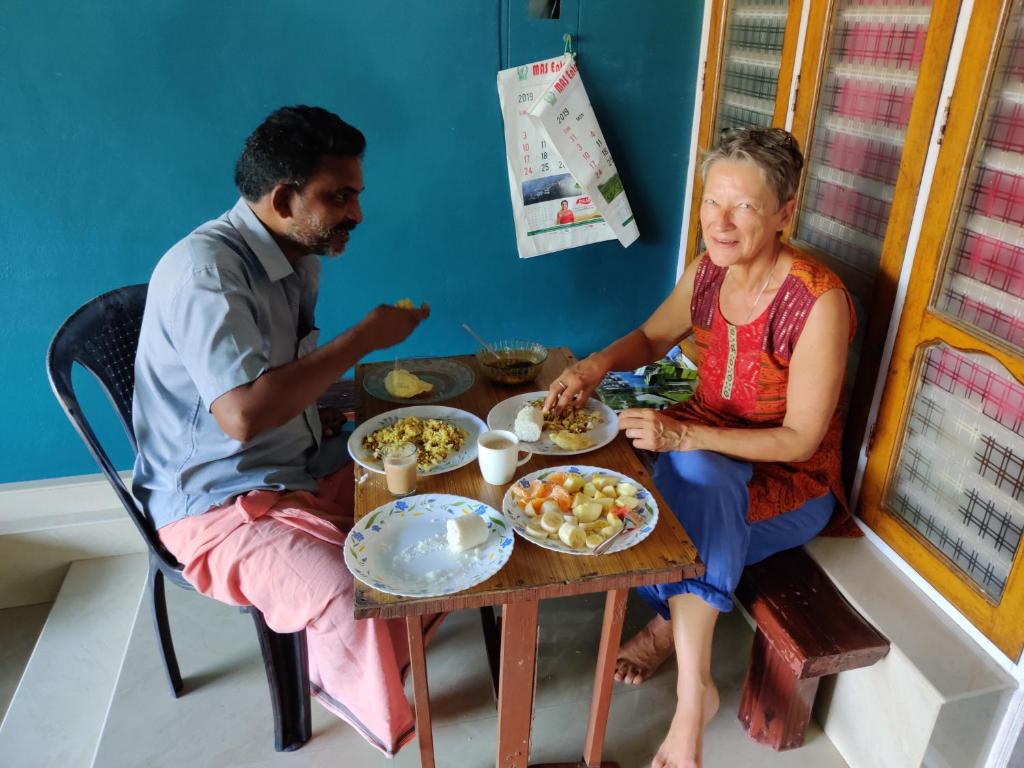 a man and a woman sitting at a table with food at Sajeev Home Stay in Cherai Beach
