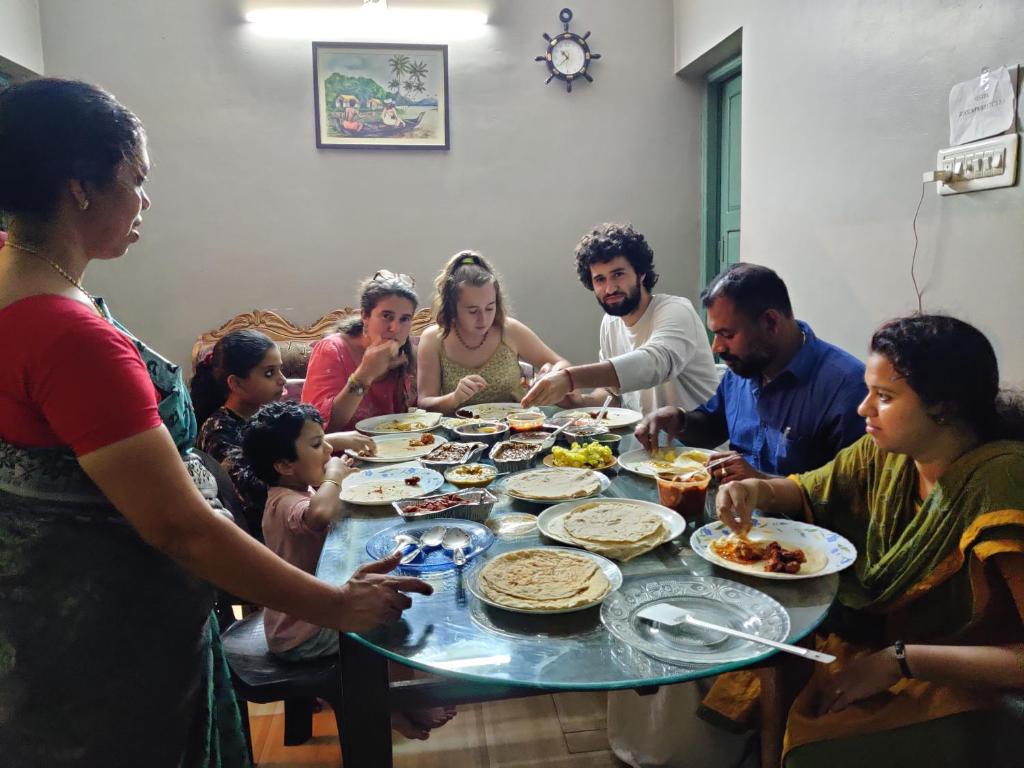 a group of people sitting around a table eating food at Sajeev Home Stay in Cherai Beach