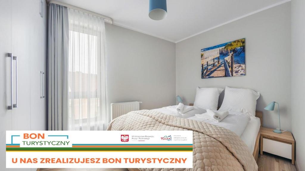 een witte slaapkamer met een bed in een kamer bij Apartament w Rezydencji Park in Mielno