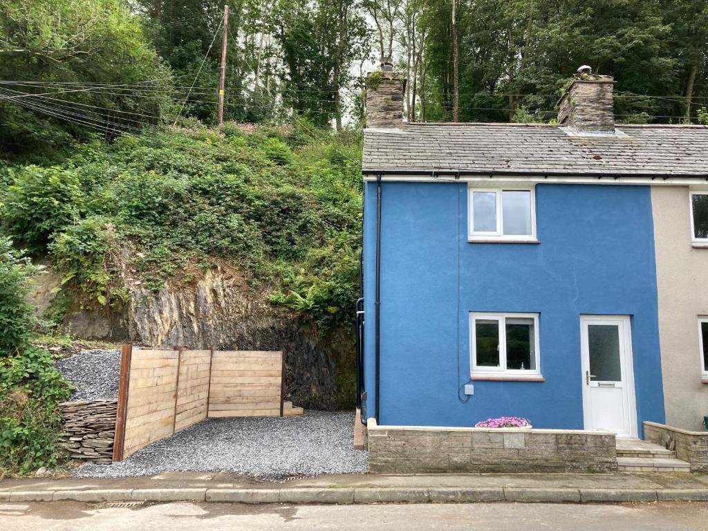 uma casa azul com um portão de madeira em frente em Ty Gles em Derwenlas