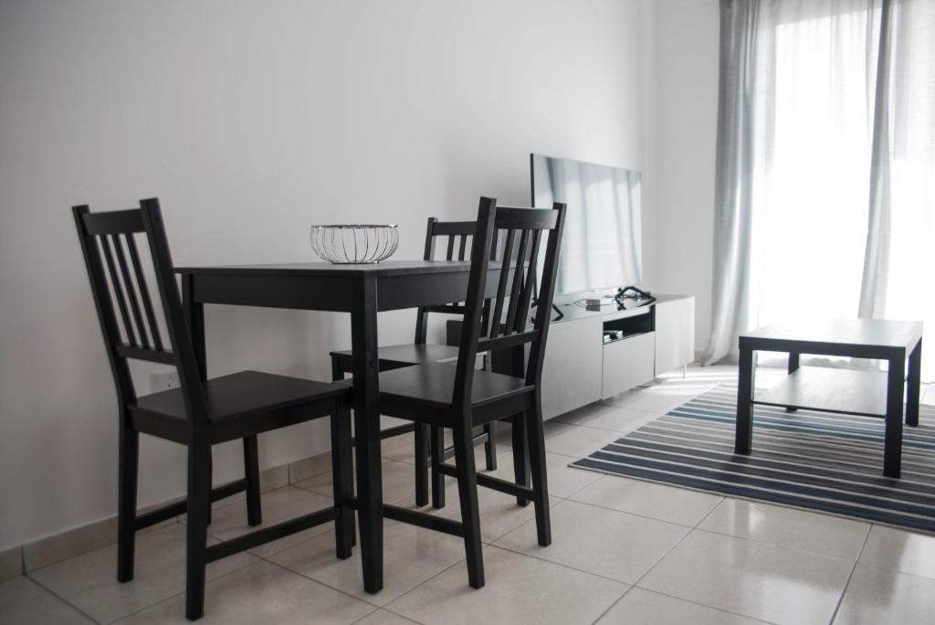 a black dining room table and chairs in a room at Renovated one bedroom apartment in Paphos with pool in Paphos