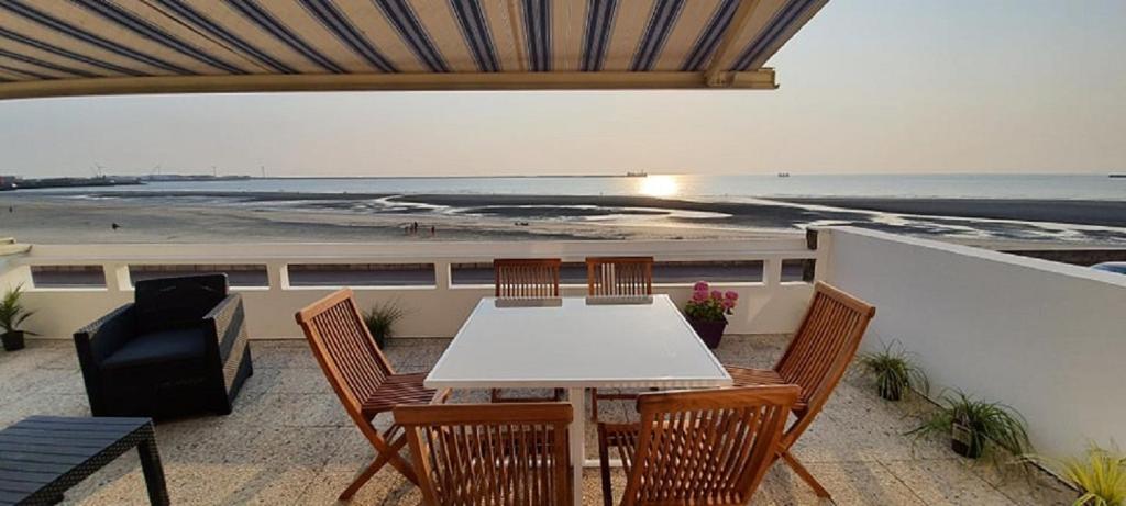stół i krzesła na balkonie z widokiem na ocean w obiekcie Superbe appartement avec terasse face à la mer w mieście Boulogne-sur-Mer