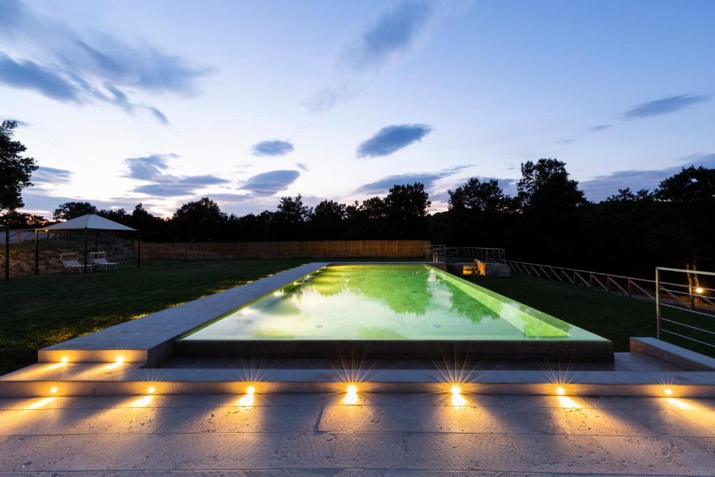 uma piscina iluminada à noite com luzes em Il Giuncheto em Trequanda