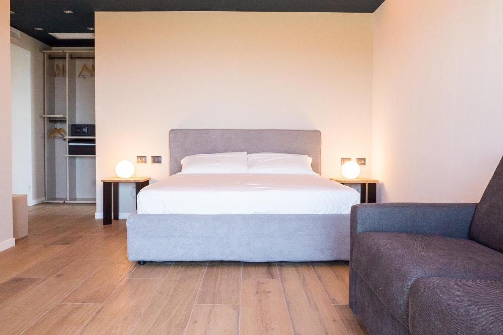 a bedroom with a white bed and a couch at Encanto Agriturismo & Private SPA in Visogliano